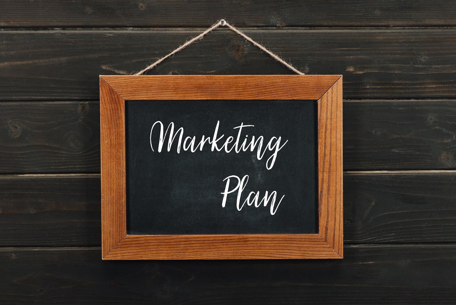 Board with lettering marketing plan hanging on wooden wall