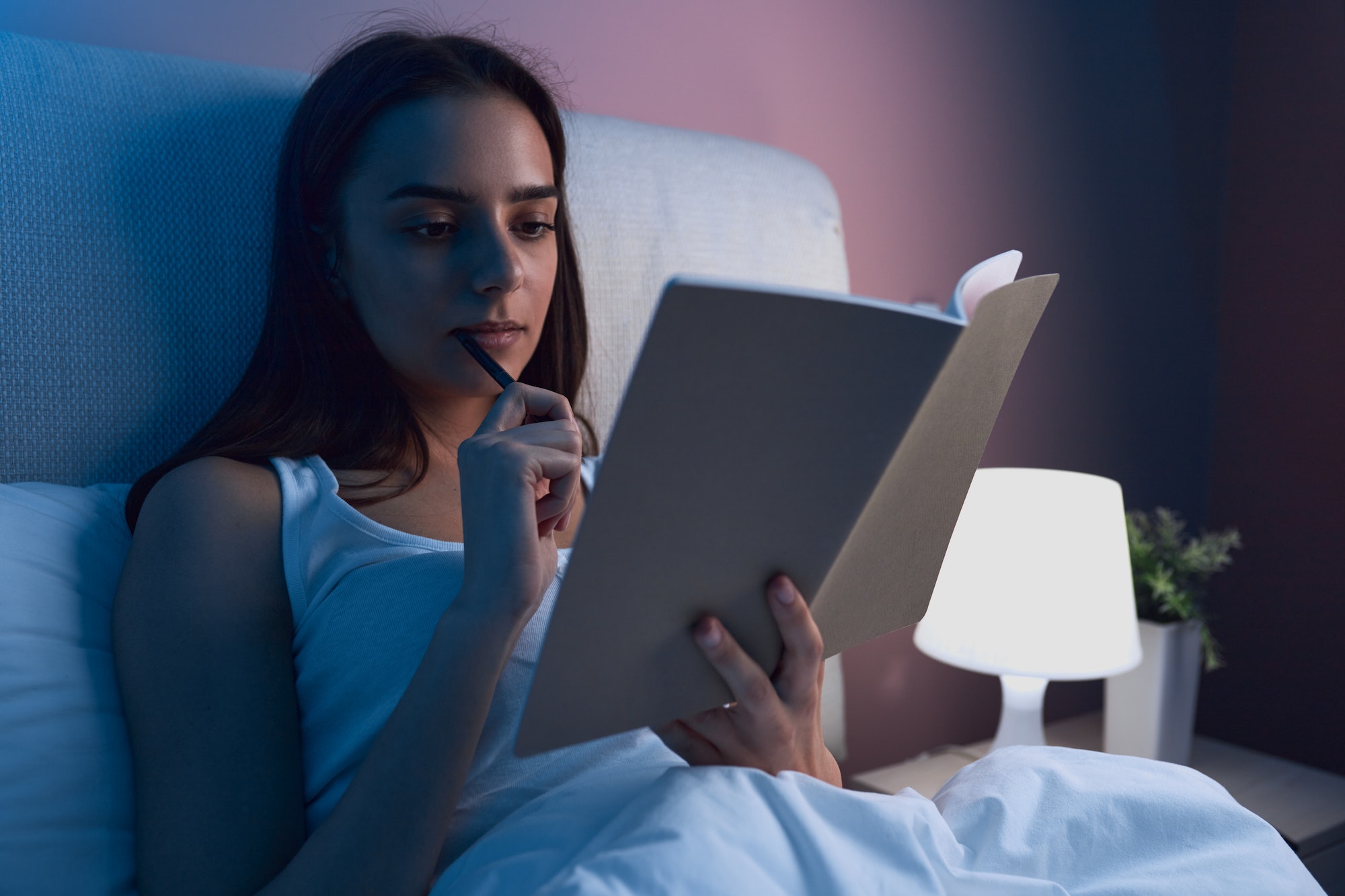 Woman writing in diary in bed